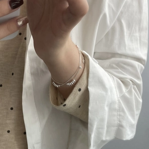 Gros plan d'un bracelet double couche en argent S925 avec perles et pendentif cœur