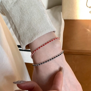 Detail of red and black minimalist woven cord bracelets with silver beads on wrist