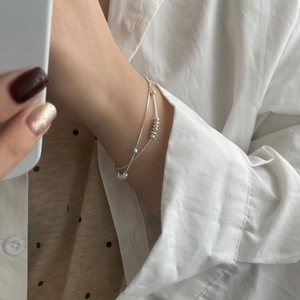 Gros plan d'un bracelet double chaîne en argent sterling S925 avec des billes polies