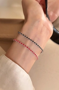 Detail of red and black minimalist braided cord bracelets with silver beads on a wrist