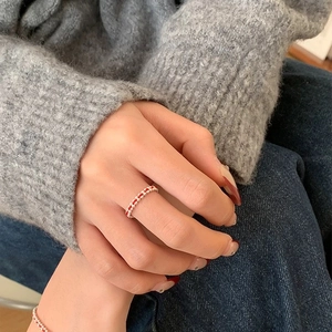 Gros plan d'une bague tressée rouge et argent portée à l'index pour un look minimaliste