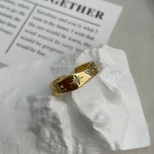 Detail of gold-plated star pattern ring with sparkling zircon and hammered texture