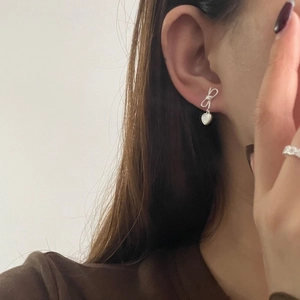 Boucles d'oreilles nœud en argent S925 avec pendentifs cœur portées par une femme