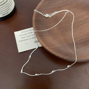 Minimalist S925 sterling silver wavy necklace with five sparkling zircons on a wooden table