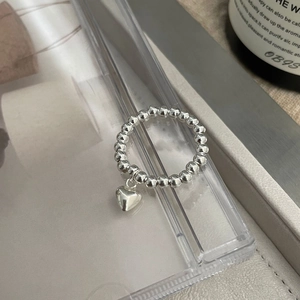 Détail d'une bague perlée en argent sterling S925 avec un petit pendentif en forme de cœur
