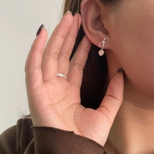 Boucles d'oreilles nœud et cœur en argent S925 portées par un mannequin avec bague