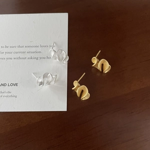 Macro detail of minimalist matte gold and silver ruffle-shaped stud earrings