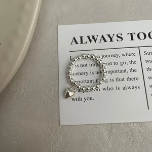 Gros plan sur une bague perlée en argent 925 avec pendentif cœur sur carte design