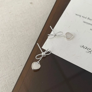 Détail des boucles d'oreilles nœud en argent S925 avec pendentif cœur en nacre blanche