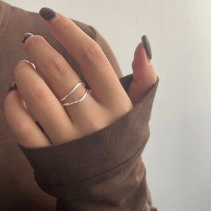 Detail shot of a minimalist double-layer wavy silver ring worn on model hand