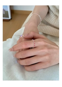 Détail d'une bague et d'un bracelet perlés en argent 925 avec un pull en maille beige