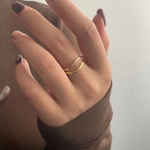Detail shot of a layered wave ring in gold finish worn on a finger with a modern style