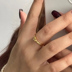 Detail showing the irregular lava texture of the gold minimalist star ring on index finger