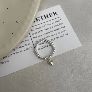 Gros plan sur la bague perlée en argent S925 avec détail de pendentif coeur poli