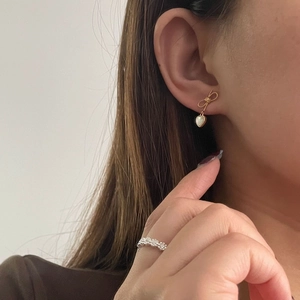 Gros plan d'une boucle d'oreille cœur dorée et d'une bague en diamant sur un modèle