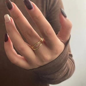 Close-up of a minimalist golden double-layered open ring worn on a finger