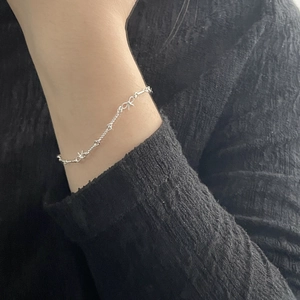 Détail du bracelet en argent S925 avec breloques étoiles porté au poignet d'un mannequin