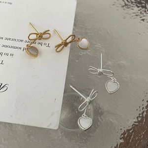 Gros plan de boucles d'oreilles nœud en argent S925 avec pendentifs cœur en nacre or et argent