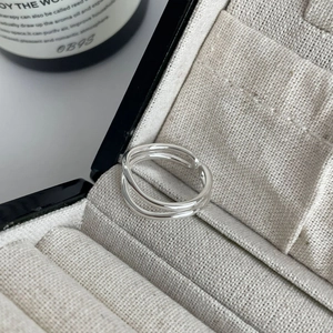 Close-up of double-layered silver ring on beige velvet display box with soft lighting