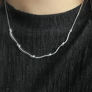 Minimalist S925 sterling silver wave necklace with zircon crystals on black knit top