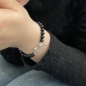 Detail of a minimalist black onyx bead bracelet with a silver OT clasp worn on a wrist