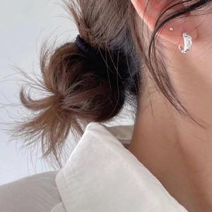 Close-up of minimalist silver hoop earring with diamond pattern worn on ear side view
