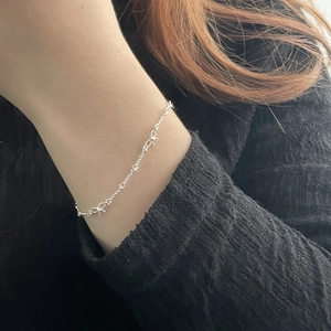 Gros plan d'un délicat bracelet à nœud en argent sur poignet avec tricot noir