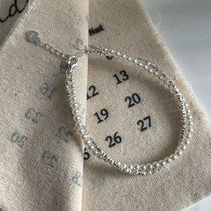 Close-up of double-layer S925 silver beaded bracelet with pearls and heart charm detail