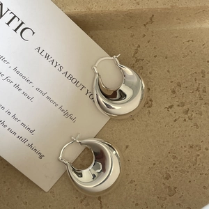 Gros plan de boucles d'oreilles anneaux creuses polies sur pierre avec carte texte
