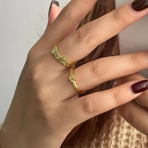 Detail shot of two gold rings with hammered lava texture on a hand in natural light