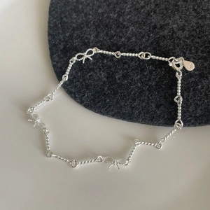 Détail d'un bracelet en argent S925 avec nœuds et chaîne torsadée, fermoir mousqueton