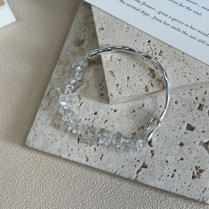 Detail of 925 silver bracelet with irregular white crystals on beige stone props