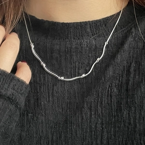 Detailed view of silver wavy pendant necklace with sparkling cubic zirconia on model