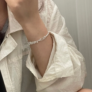 Detail of silver S-hook bracelet featuring irregular clear crystal stones on wrist