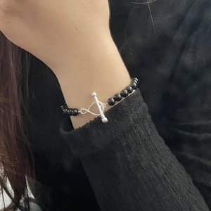 Close-up of S925 silver infinity clasp bracelet with black onyx beads on wrist