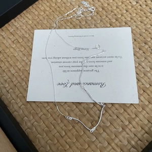 Detail view of S925 sterling silver wavy necklace with sparkling cubic zirconia on a white card