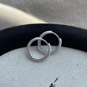 Macro shot of S925 sterling silver hoop earrings with a brushed matte finish texture