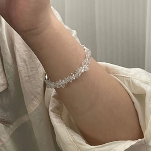 Irregular clear white crystal beaded bracelet with metal clasp on person's wrist