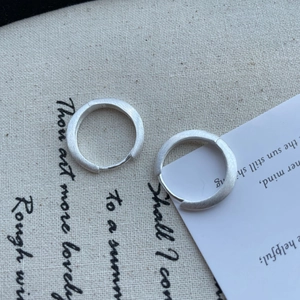 Close-up of minimalist S925 silver hoop earrings with a matte brushed metal texture