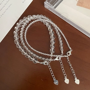 Three transparent crystal bead bracelets with S925 silver heart charms on wood