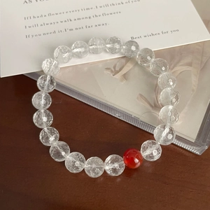Minimalist faceted crystal beaded bracelet with a single red agate bead on wood