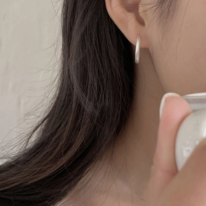 Close-up of minimalist silver hoop earrings on model featuring a brushed metallic finish