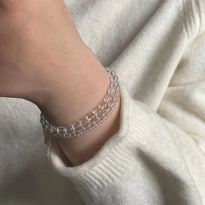 Detail of double-layer clear crystal bead bracelet worn on wrist with knitted sweater
