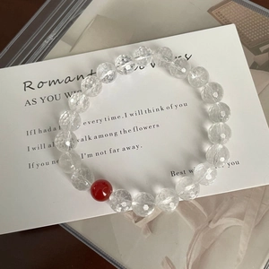 Detail of faceted clear crystal bracelet featuring a single red agate bead on a card