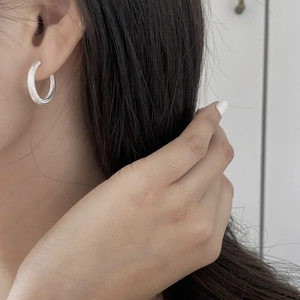 Detailed close-up of a brushed silver minimalist hoop earring worn by a model