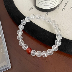 Macro shot of faceted white crystal beads with a single red agate on a beaded bracelet