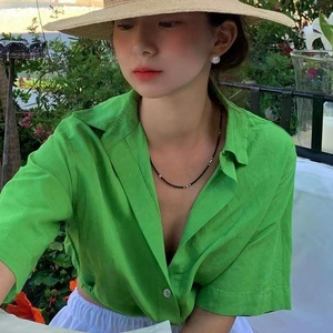 Détail d'un collier de perles avec chemise en lin vert et accessoires de style estival