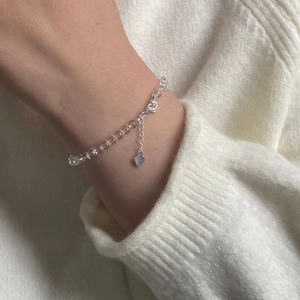 Macro shot of S925 sterling silver heart charm and clear crystal beads on a wrist