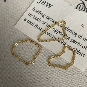 Trois bagues minimalistes en chaîne souple dorée présentées en un style vintage