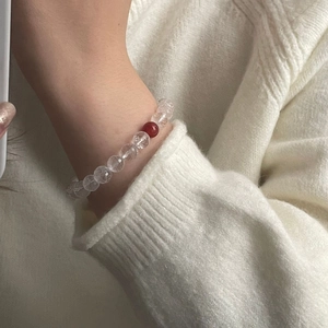Detailed shot of faceted clear crystals and red agate bead on a minimalist beaded bracelet